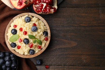 Bowl of tasty couscous with blueberries, pomegranate and mint on table, flat lay. Space for text