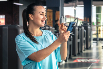 Active young woman using smartphone in fitness gym.