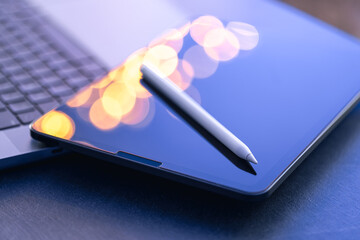 Digital tablet, stylus pen and laptop on the desktop, close up.