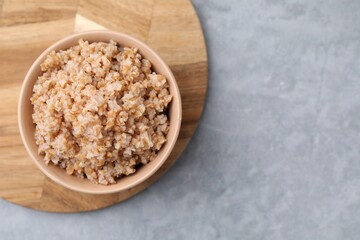Tasty wheat porridge in bowl on grey table, top view. Space for text