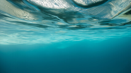 Underwater view of clear blue sea water surface with waves and bubbles, copy space
