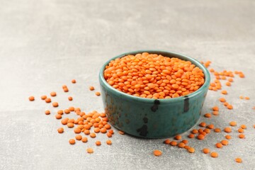 Raw red lentils in bowl on light table, closeup. Space for text