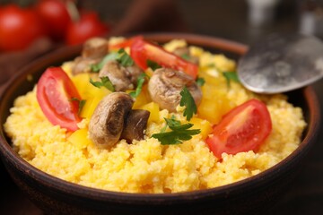 Tasty cornmeal with tomatoes, pepper and mushrooms in bowl on table, closeup
