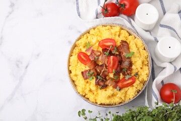 Tasty cornmeal with tomatoes, bacon and microgreens in bowl served on white marble table, flat lay. Space for text