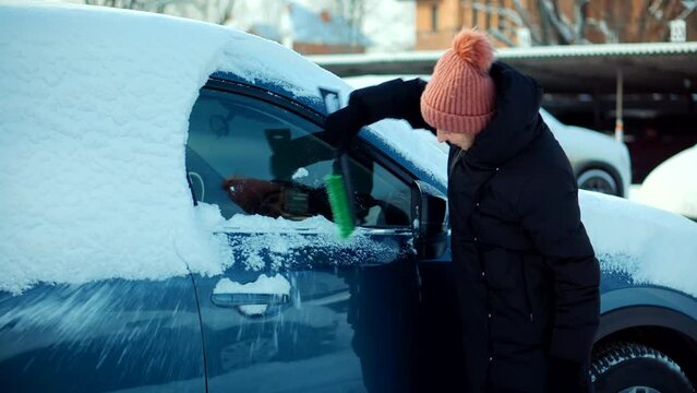 woman scratching ice from car windows	