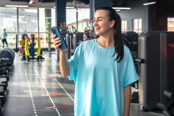 Happy young woman athlete talk on a phone at gym, copy space.