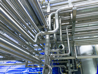 Stainless steel pipes in the factory. Construction on food production, industry background.