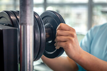 A muscular sportswoman putting weight plates in a gym for bodybuilding.