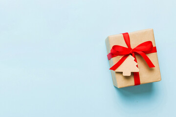 wrapped christmas or other holiday handmade present in paper with colored ribbon. Present box, decoration of gift on colourfull table, top view with copy space