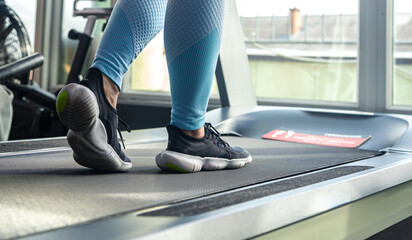 Woman's legs on a treadmill, shoes close-up, cardio workout.