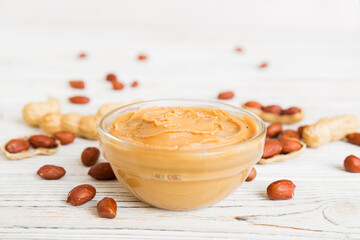Bowl of peanut butter and peanuts on table background. top view with copy space. Creamy peanut pasta in small bowl