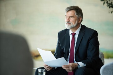 Focused serious mature businessman professional lawyer executive holding paper checking document...