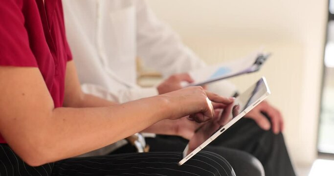 Closeup of two partners discussing joint project using tablet computer