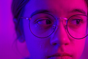 Cute girl with glasses crying in neon light, face close-up. - obrazy, fototapety, plakaty
