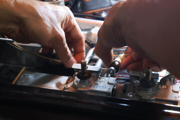 Close up of a technician's hand repairing a broken cooktop or stovetop