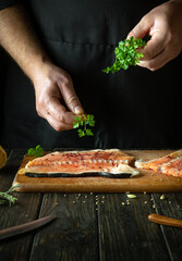 Adding parsley to fish steaks for aroma and taste. European cuisine. The process of preparing fish by the hands of a chef in a restaurant or hotel kitchen