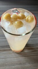 Top view healthy iced star gooseberry drink for detoxification falling in glass.	