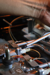 Close up of a technician's hand repairing a broken cooktop or stovetop