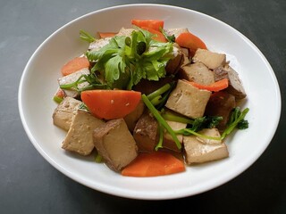 Table top view sauteed soft tofu with vegetable isolated on black background.