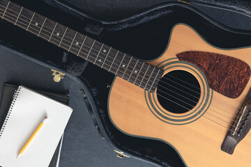 Acoustic guitar and notepad with pencil, top view.
