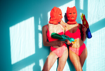 Two beautiful sexy women in red underwear. Models wearing bandit balaclava mask. Hot seductive...