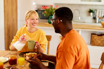 Obraz na płótnie Canvas Multiracial couple enjoying breakfast together at home