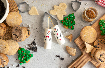 Marshmallow snowmen and homemade cookies on the kitchen table, top view.