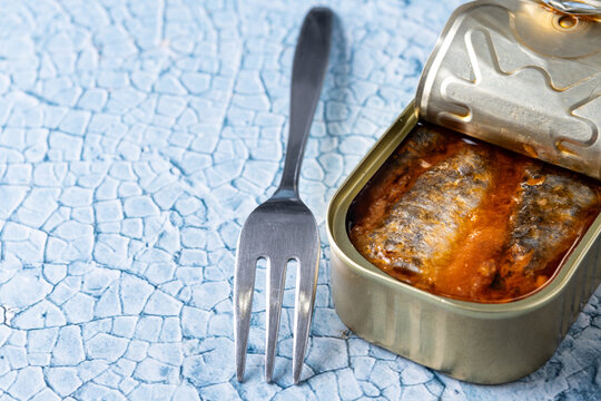 Canned sardines in metal can on blue background. Copy space