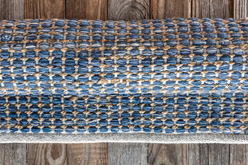 Hand woven geometric denim area rug on wooden floor.