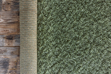 Background of texture of a green carpet with long pile on wooden floor.