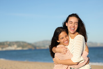 Two funny friends hugging on the beach