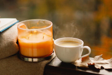 Sweet Home. Still life details in home on a wooden window. Sweater, candle, hot coffee and autumn decor. Autumn home decor. Cozy fall mood. Cozy autumn or winter concept.