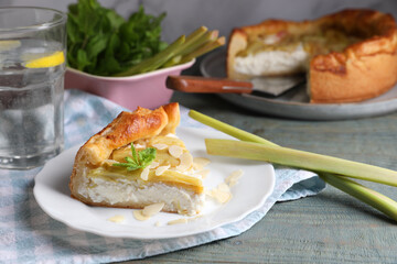 Freshly baked rhubarb pie with cream cheese, stalks and almond flakes on grey wooden table