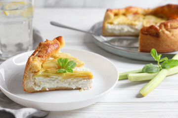 Freshly baked rhubarb pie with cream cheese, stalks and mint leaves on white wooden table, closeup