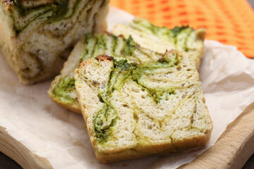 Slices of freshly baked pesto bread on wooden board, closeup