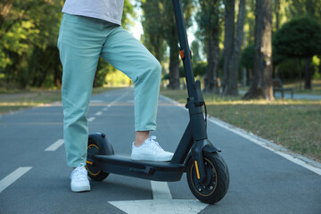 Obraz premium Woman with modern electric kick scooter in park, closeup