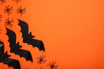 Flat lay composition with paper bats and spiders on orange background, space for text. Halloween...