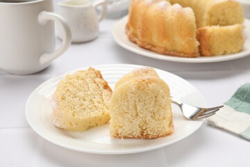 Pieces of delicious sponge cake and fork on white table, closeup
