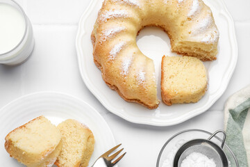 Delicious sponge cake served on white tiled table, flat lay