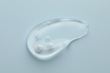 Smear of clear cosmetic gel on light blue background, top view