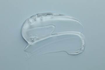 Smear of clear cosmetic gel on light blue background, top view