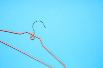 Empty orange hanger on light blue background, top view. Space for text