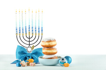 Hanukkah celebration. Composition with menorah, dreidels and donuts on table against white background