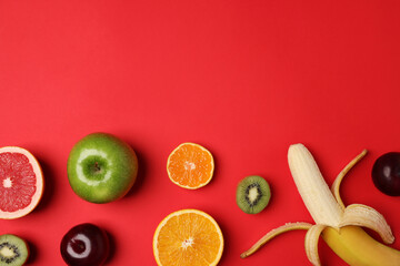 Different ripe fruits on red background, flat lay. Space for text