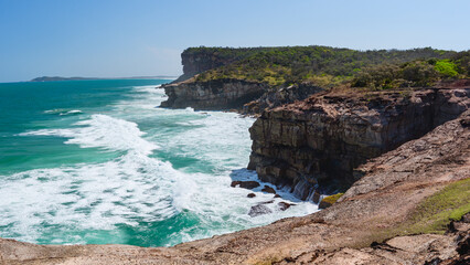 Australian coast, high cliffs on the seashore, seaside landscape with blue water, view from the cliff on a sunny summer day.
