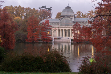 views of the glass palace of the parque del retiro in madrid in autumn with its pond in front of...