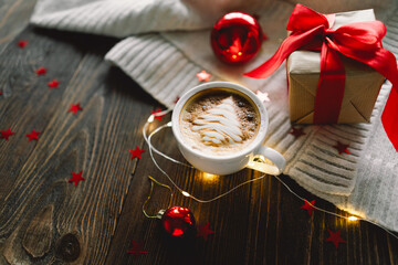 Christmas cup of coffee with sweater and Christmas decorations together with lights bokeh on a wood background. Holiday atmosphere. Winter mood, holiday decoration