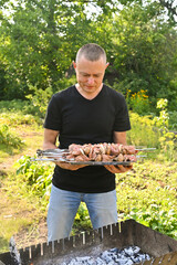 a man puts a skewer with meat on the grill