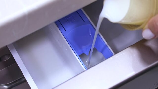 Pour laundry detergent gel into the washing machine container. Using fabric softener for laundry