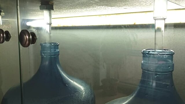 Production. Filling open necks of PET bottles with water. Large empty plastic bottle. 